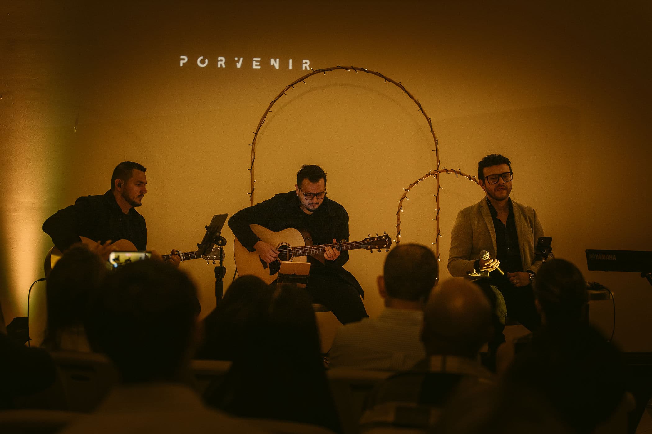 Músicos y público reunidos bajo arcos iluminados durante un encuentro de PORVENIR